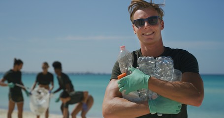 Portrait of an young male volunteer with sunglasses is smiling in camera satisfied with picking up...