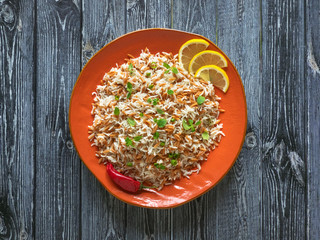 Oriental rice pilaf with orzo in a plate on a dark background. Top view.