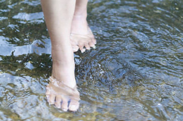 Woman feet walking on the water in the river for relax feeling