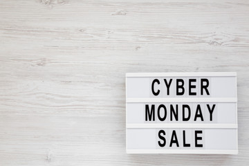 'Cyber monday sale' words on a lightbox on a white wooden background, top view. Overhead, from above, flat lay. Space for text.