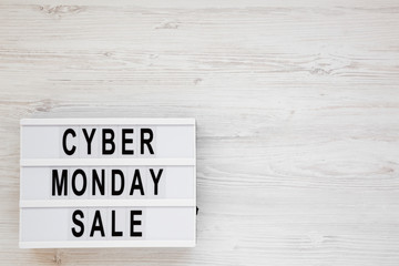'Cyber monday sale' words on a lightbox on a white wooden surface, top view. Overhead, from above, flat lay. Copy space.