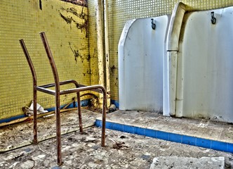 Fototapeta na wymiar Des urinoirs abandonnés. Des vieilles pissotières abandonnées. Une vieille chaise cassée. Un bâtiment abandonné. Des toilettes abandonnées. Des WC abandonnés