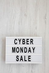 'Cyber monday sale' words on a lightbox on a white wooden background, top view. Overhead, from above, flat lay. Copy space.