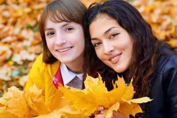 woman having fun with autumn leaves in city park, outdoor portrait