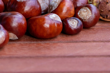 Ein frischer Haufen schöner Kastanien liegt auf einem braunen Tisch bereit zum kreativen Basteln mit Kindern im Herbst und Winter
