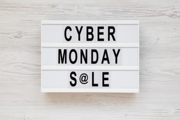 'Cyber monday sale' words on a lightbox on a white wooden background, top view. Overhead, from above, flat lay. Close-up.