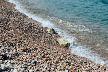 Beach, wet pebbles, seashore and waves-the sea beach and the concept of a beach holiday.