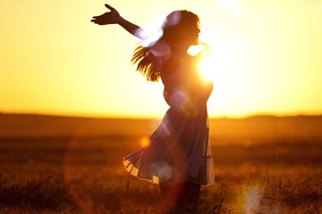 Young woman on field under sunset light
