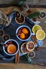 Hot mulled wine in gray metall mugs with orange and spices Rustic style