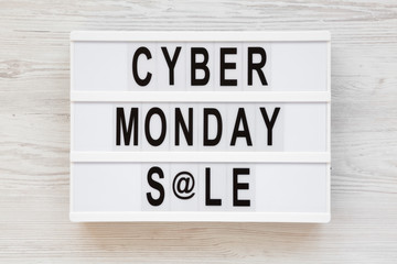 Fototapeta premium 'Cyber monday sale' words on a modern board on a white wooden surface, top view. Overhead, from above, flat lay. Closeup.