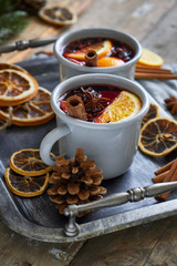 Mulled wine in two gray metall mugs with orange and spices Rustic style On wooden background