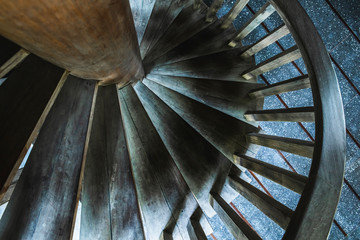 Detail of wooden spiral staircase, abstract geometric wallpaper in dark tones. Round stairs....
