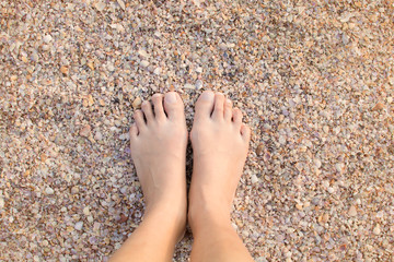 Asian female barefoot stand on the beach sand with sea shells, beach of Krabi, Thailand