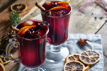 Christmas mulled wine in two glasses with fruits and spices on wooden background