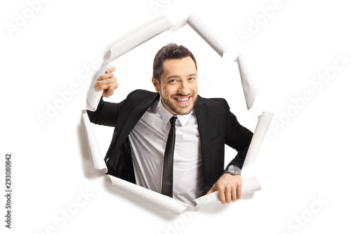 Young man in suit looking through a paper hole