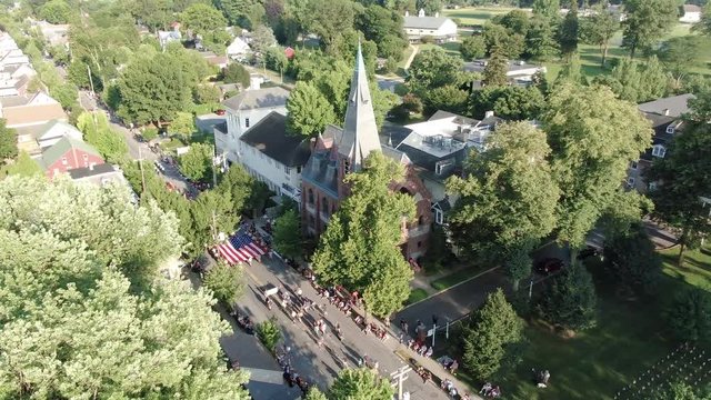 Cinematic high aerial of church along parade route on Independence Day in Lititz, Lancaster County, Pennsylvania