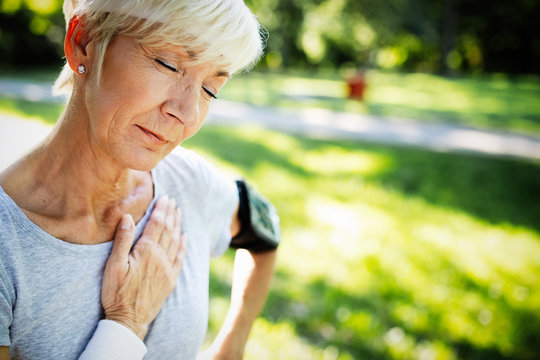 Senior woman with chest pain suffering from heart attack during jogging