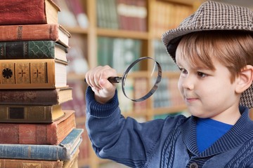 Cute little boy with old books and magnifying glass