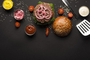Top view classic burger surrounded by sauces
