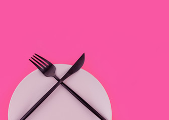 Pink plate and cutlery on the pink background.