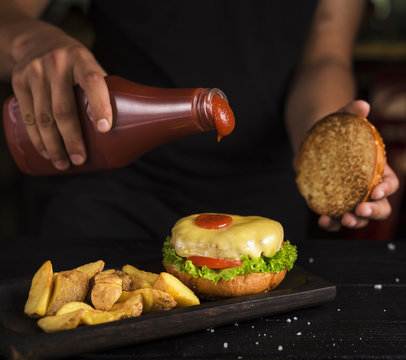 Man Pouring Ketchup On Tasty Beef Burger