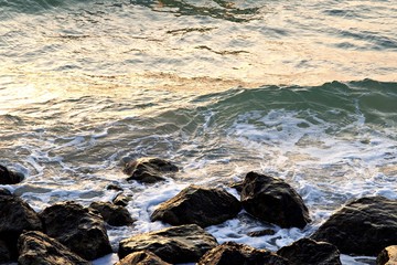 Rocky beach in uae . Waves splashing on rocks in sunny day . beach at the sunset , Waves crashing into the Rocks