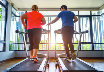 man trainer coach and fat woman being run or jog on belt of treadmill machine, workout under...