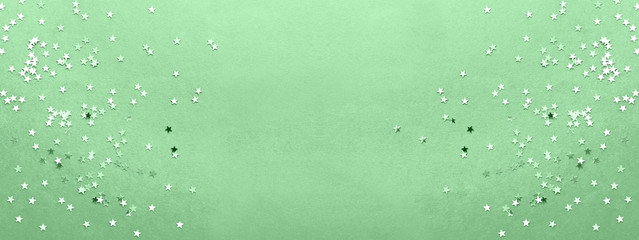 Holiday background with silver star confetti on neo mint colored background. Good backdrop for Christmas and New Year cards.