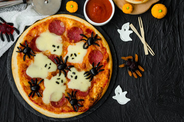Halloween Pizza Monsters with cheese Ghost and olive Spider on a black background. Food idea for Halloween party.