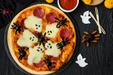 Halloween Pizza Monsters with cheese Ghost and olive Spider on a black background. Food idea for Halloween party.
