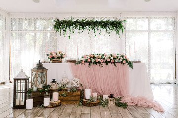 Beautiful groom and bride table near large light windows decorated with natural materials