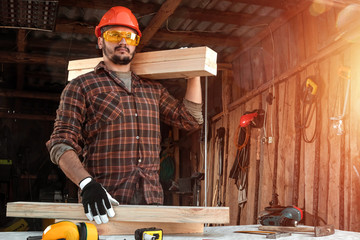 Builder man carries boards on his shoulder. Construction work, repair.