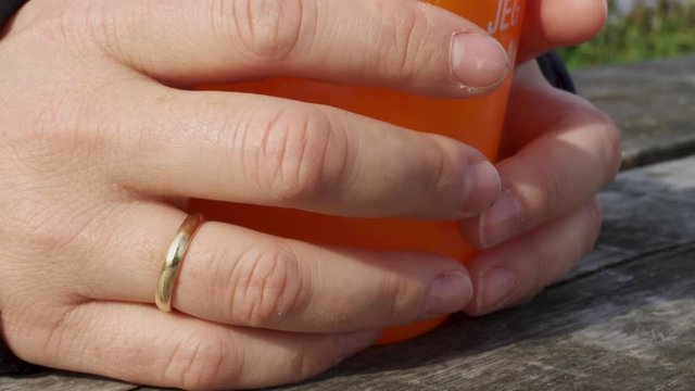 clluse up of a womans hans holdring an orange plastic bootle
