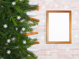 Christmas background with fir branches, cinnamon, cones, snowflakes and frame on brown wooden background. Winter holidays concept