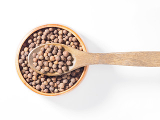 Allspice (Jamaica pepper) in the wooden cup and spoon horizontally on white background