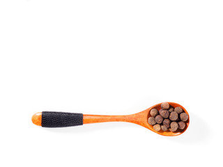 Allspice (Jamaica pepper) in wooden spoon horizontally on white background