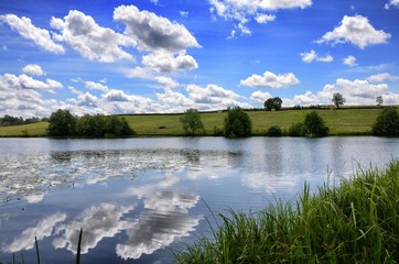 Un paysage de lac avec des nuages blancs dans un ciel bleu. Etang Fouché à Arnay-le-Duc.