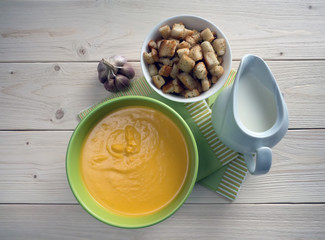 Pumpkin soup with croutons on a wooden table.