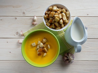 Pumpkin soup with croutons on a wooden table.