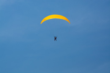 Skydiver with a yellow parachute on a background of blue clear sky