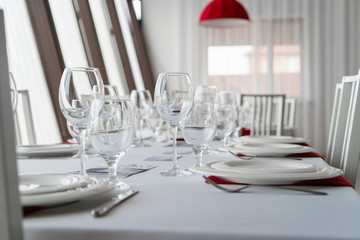 A closeup of table set with plates, glasses and chairs