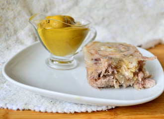 Jelly with meat, beef jelly, traditional Russian dish, serving on a plate, mustard, bread, tomatoes. Side light. Close-up.