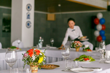 A close up of restaurant table set with the waitress in the backgroung