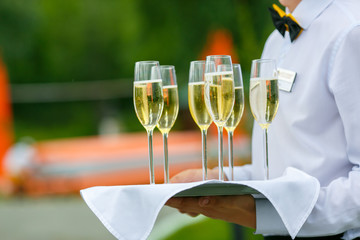 A waiter is serving a few glass of champagne on the tray