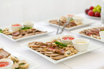 A close up of square plates with meat assorted