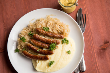Kleine Bayrische Nürnberger Rostbratwürste mit Sauerkraut, Kartoffelpüree und Senf auf Holz Tisch Hintergrund