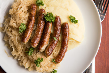 Kleine Bayrische Nürnberger Rostbratwürste mit Sauerkraut, Kartoffelpüree und Senf auf Holz Tisch Hintergrund