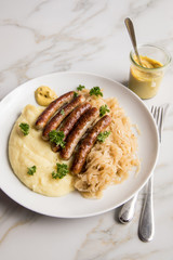 Kleine Bayrische Nürnberger Rostbratwürste mit Sauerkraut, Kartoffelpüree und Senf auf Marmor Tisch Hintergrund
