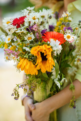 A lady is holding bouquet of wild flowers in her hands