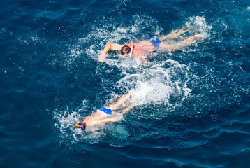 Fototapeta na wymiar People swim in the blue water of the sea